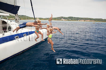 Happy friends jumping off catamaran into Caribbean Sea