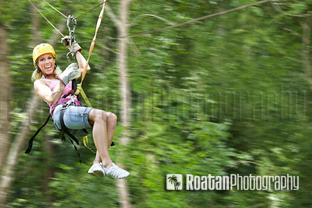 Confident woman flying through jungle on zipline stock photo