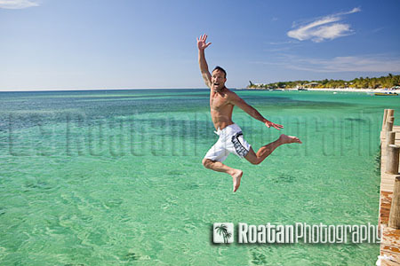 Excited man midair jumping into Caribbean Sea stock photo