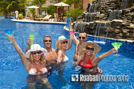 Five attractive adults enthusiasticly toasting in resort swimming pool stock photo