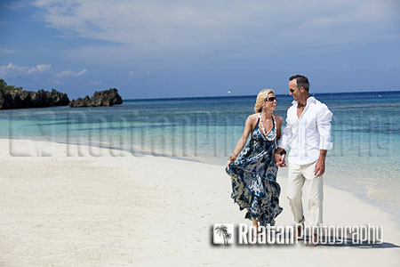 Happy mature couple walking on tropical beach stock photo