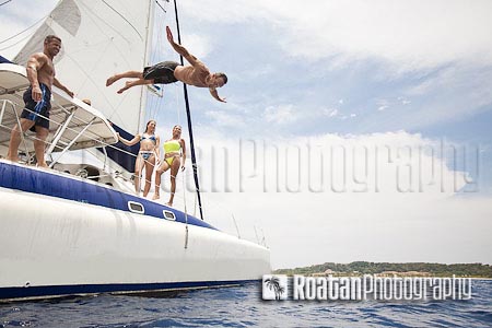 Man jumping off sailboat into Caribbean Sea stock photo